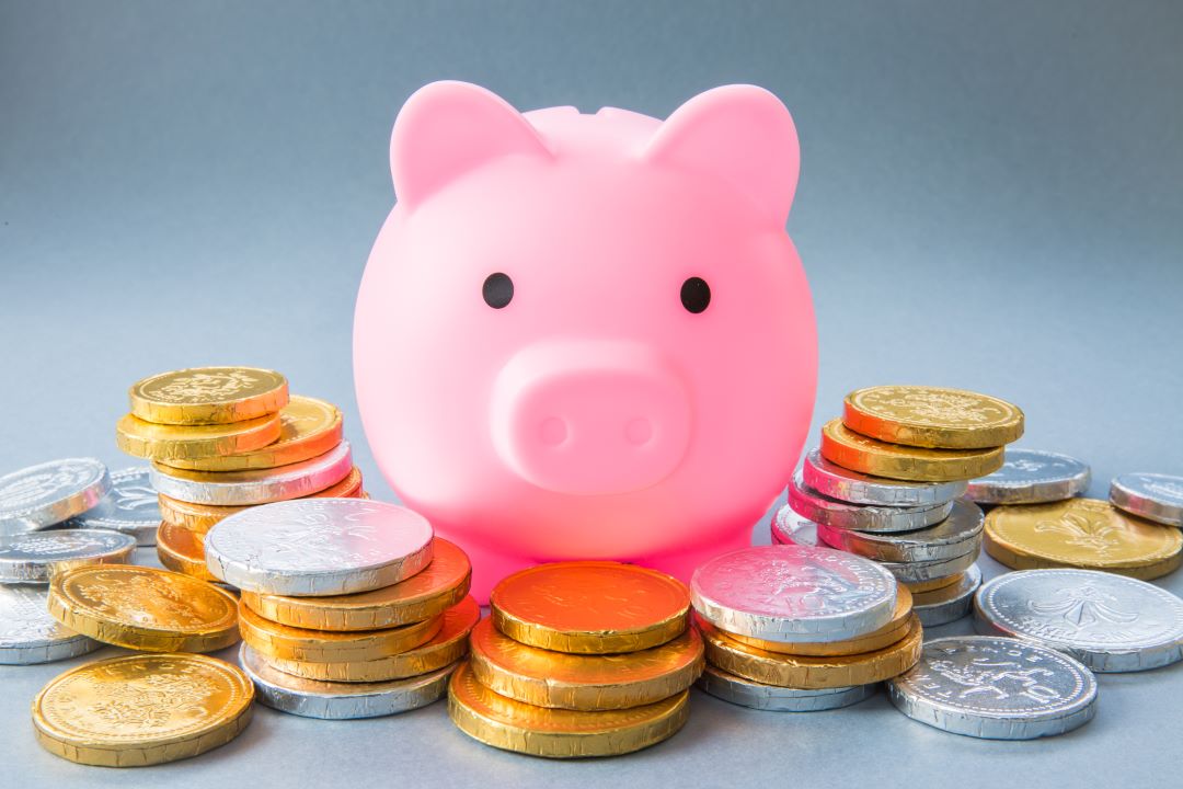 pink piggy bank surrounded by coins for article by kelley way about funding my trust