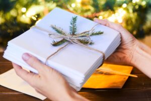 A woman gifting a stack of papers or manuscript that is tied with a bow for article by kelley way titled how do i gift my copyright